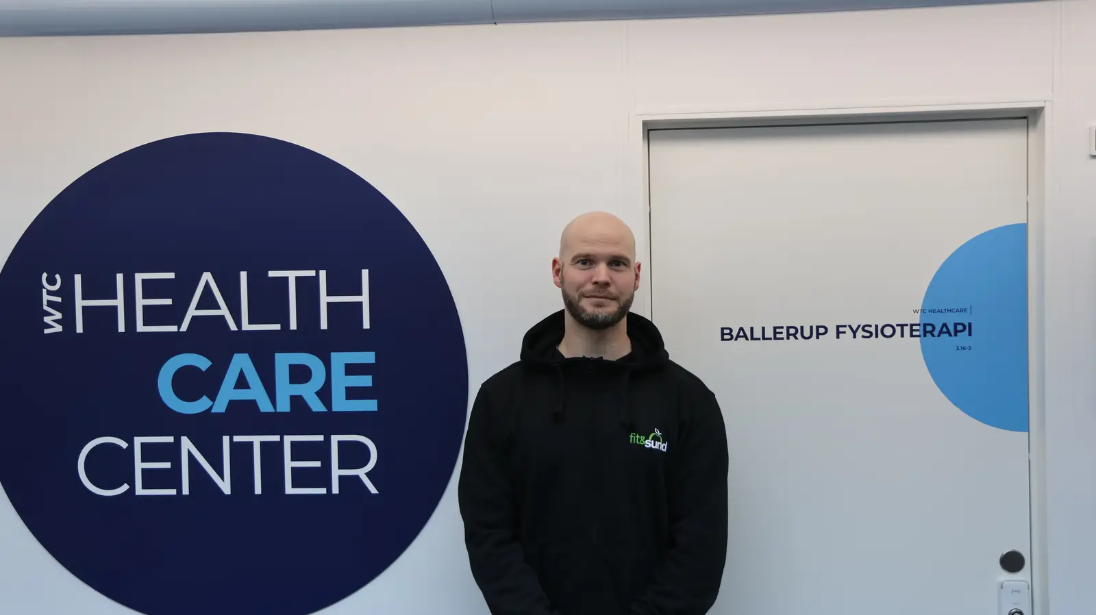 David Brink foran døren til Ballerup Fysioterapi, lokale 3.16-3, i WTC Health Care Center.