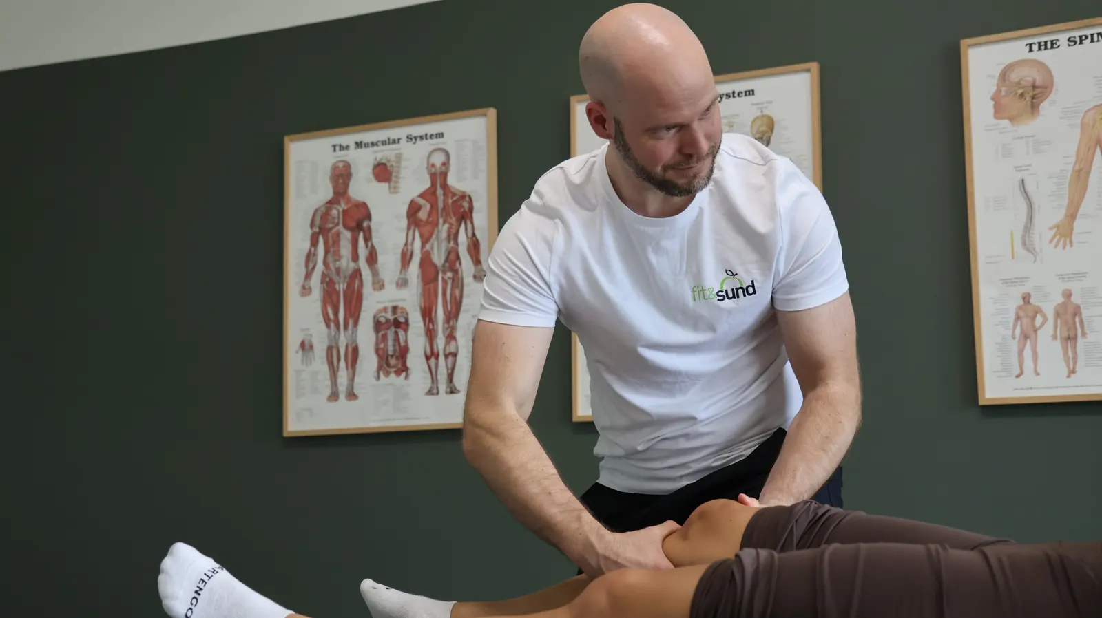 David Brink smiler til patienten, mens han behandler et knæ i klinikken i WTC Ballerup.