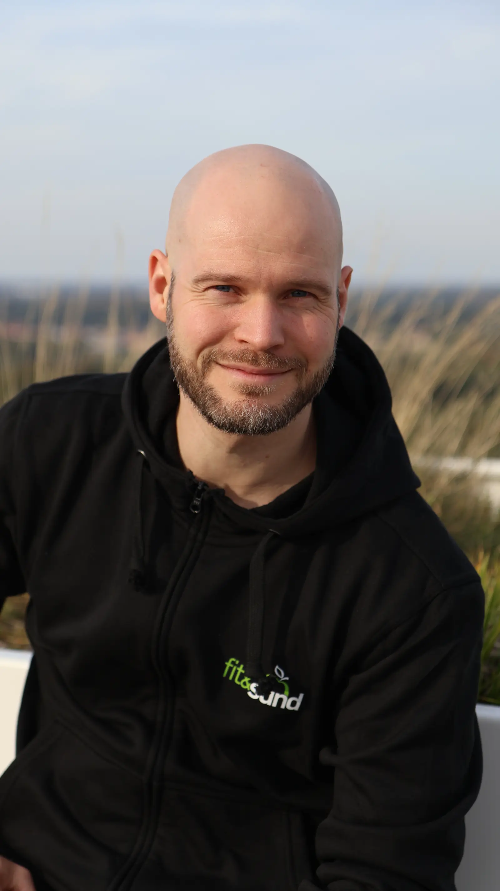 Portræt af David Brink, der sidder udendørs og smiler.
